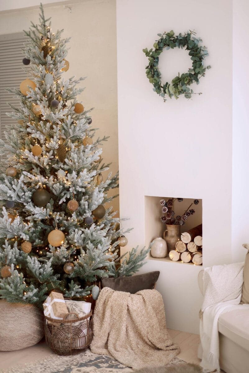Cozy minimalist room with a decorated Christmas tree and festive wreath.