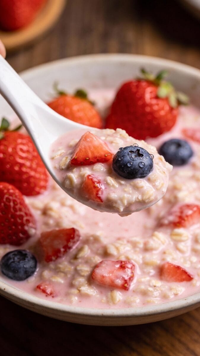spoonful of creamy strawberry oatmeal topped with fresh berries