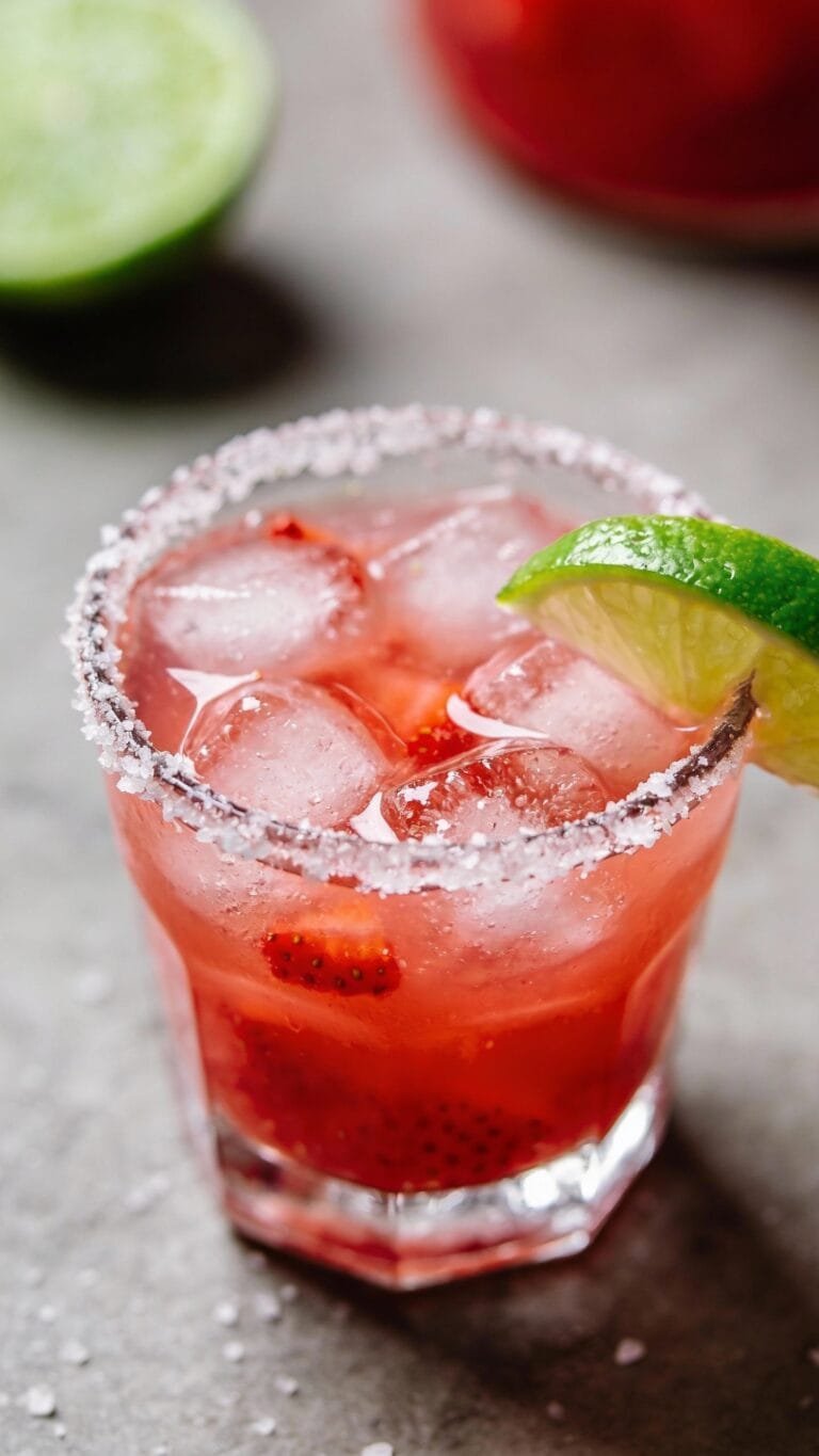 strawberry margarita on the rocks, salted rim, lime wedge
