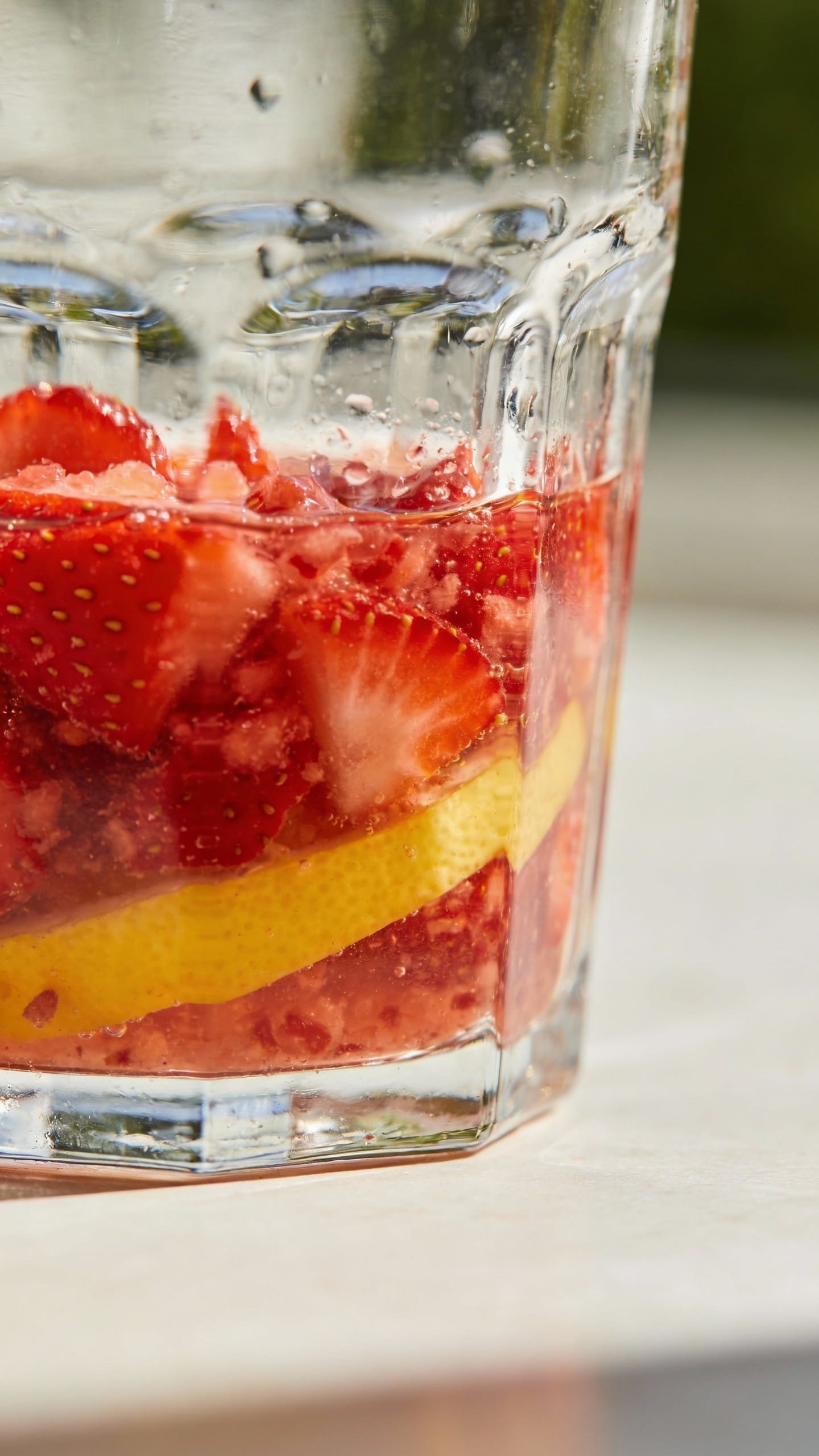Muddling strawberries and lemon in clear rocks glass