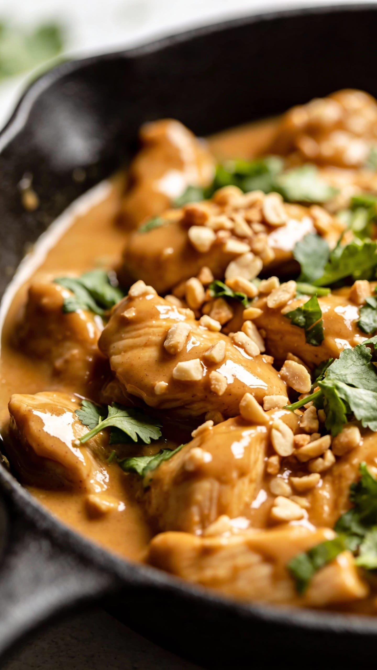 Thai peanut chicken in skillet with glossy peanut sauce